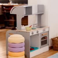 Kinderfreundliche Spielk&uuml;che aus Holz mit realistischen Details wie Herd, Sp&uuml;le und Backofen. Daneben steht ein bequemer, gestapelter Hocker in Pastellfarben. Die freundliche Atmosph&auml;re l&auml;dt zum kreativen Rollenspiel im Kinderzimmer ein.