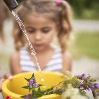 Kinder gießen Sommerblumen im Freien